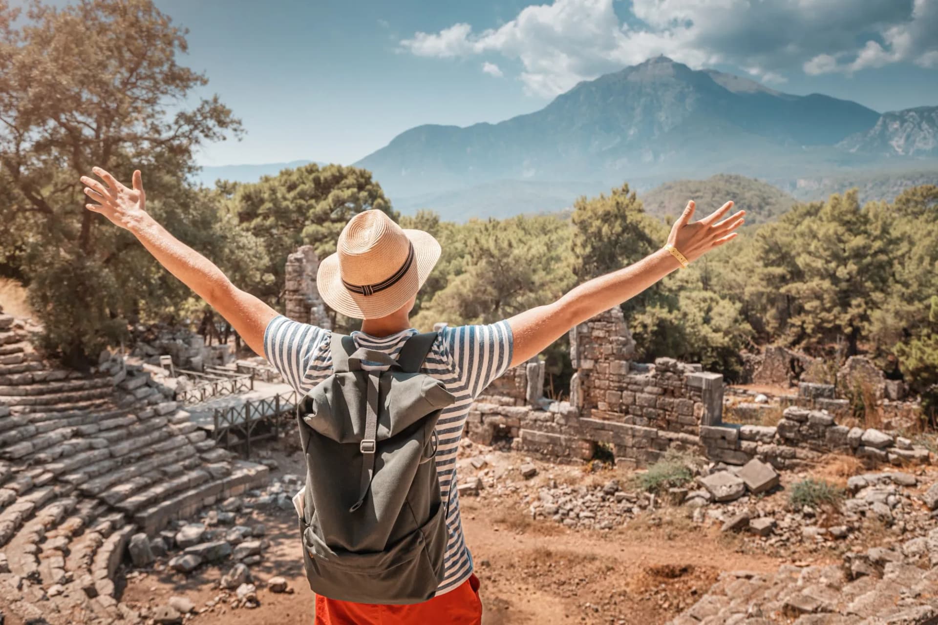 Male traveler explores the ruins of an ancient amphitheatre in antique Greek city. Wanderlust and backpacking concept