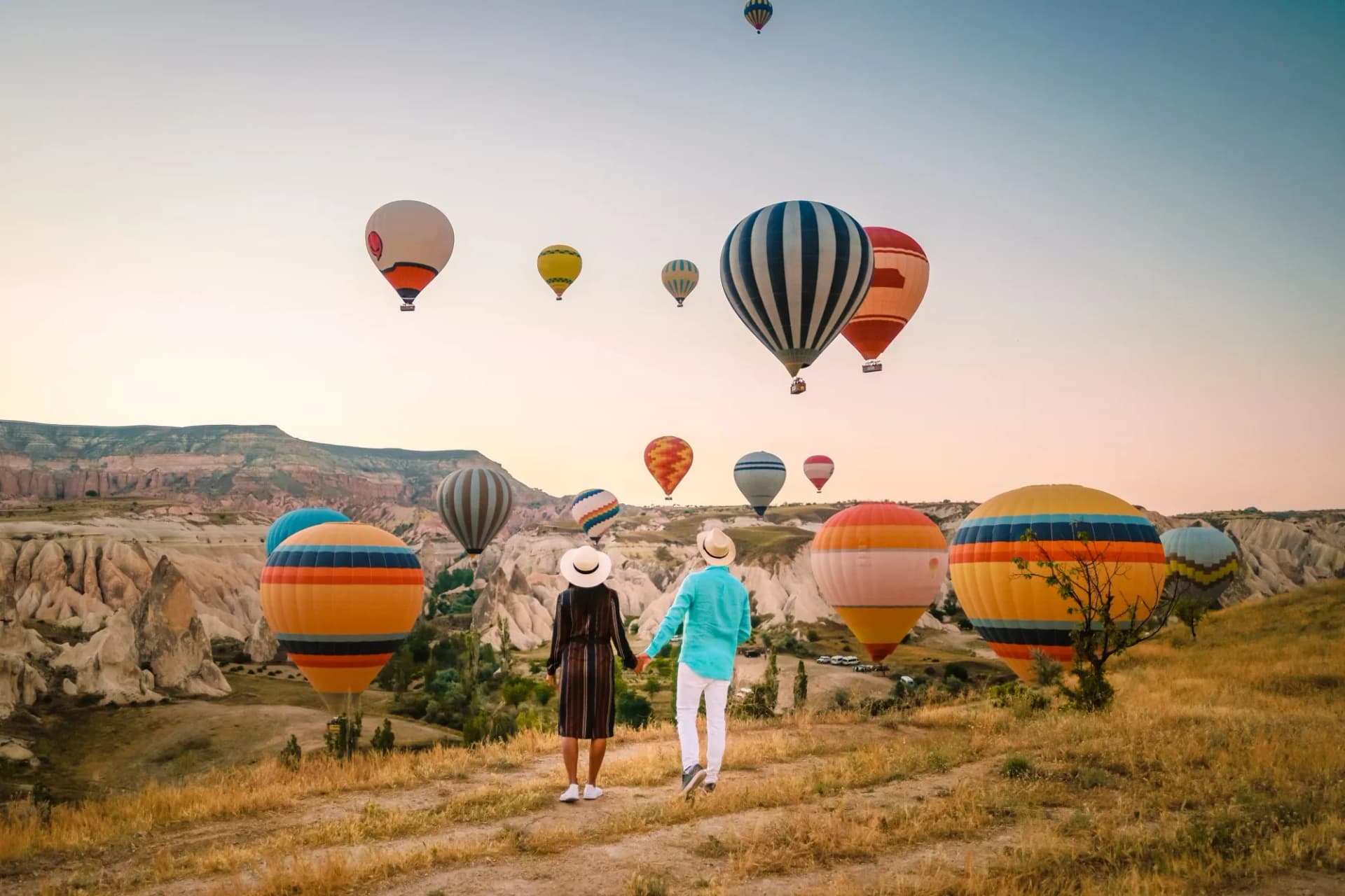 happy young couple during sunrise watching the hot air balloons of Kapadokya Cappadocia Turkey