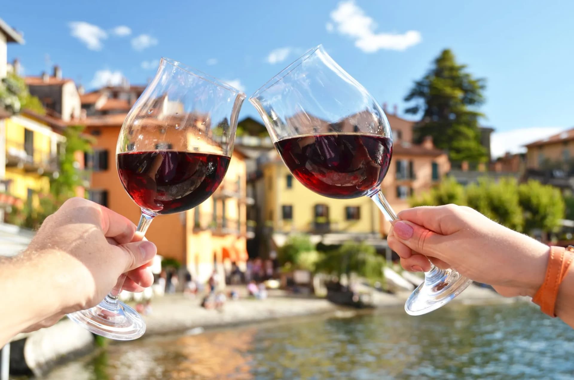 Two wineglasses in the hands. Varenna town at the lake Como, Ita