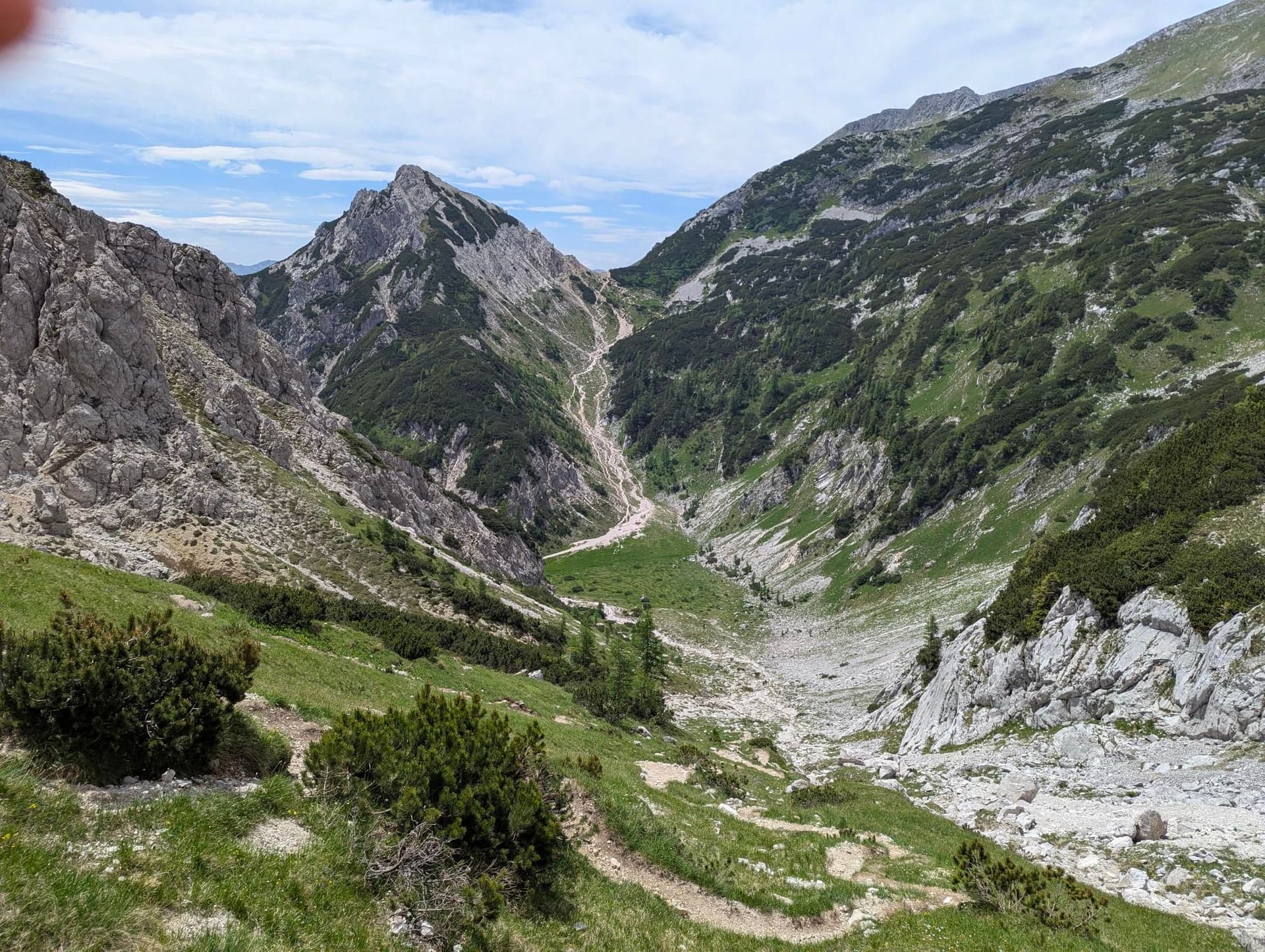 Rocky mountain valley with green slopes and a hiking trail in the Pokljuka region.