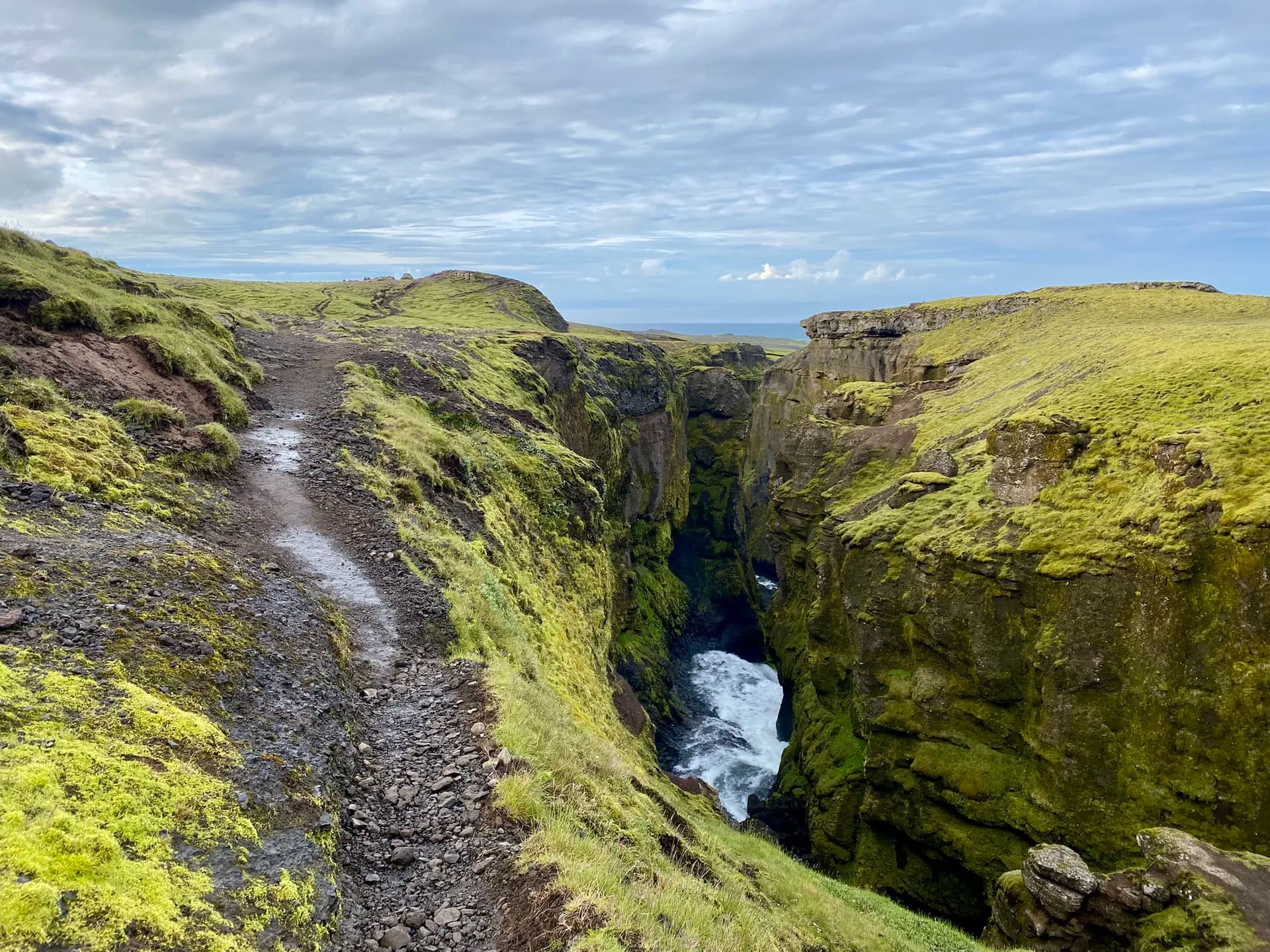 Hiking trail along a deep mossy canyon with a river at Fimmvörðuháls, Iceland.