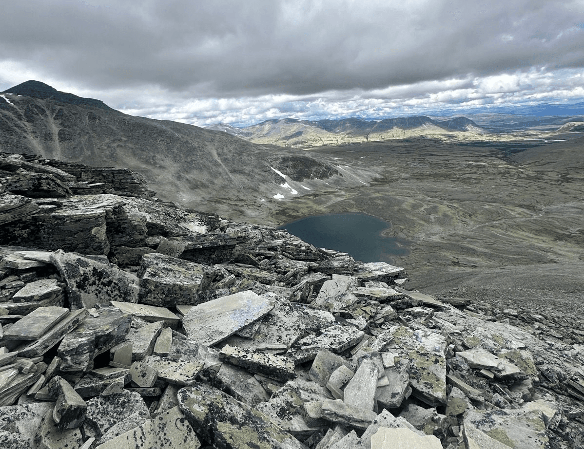 Rocky mountain landscape in Rondane National Park with a small lake and cloudy sky.