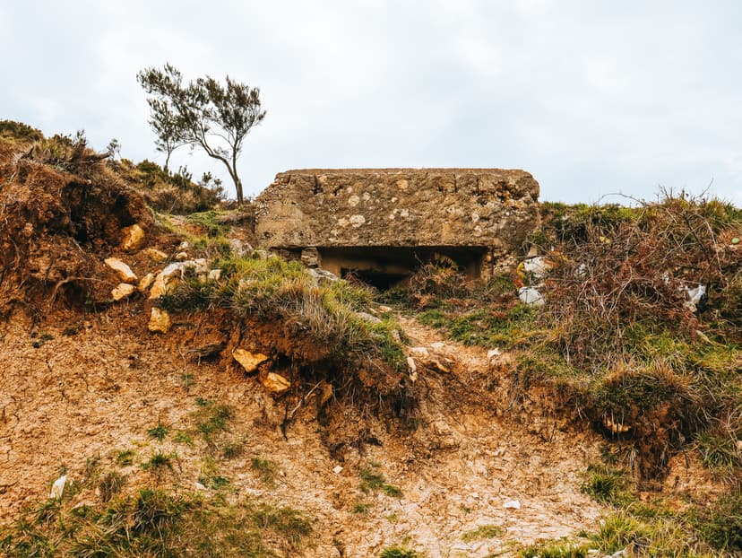 Concrete military bunker built into an earthen hillside with sparse vegetation