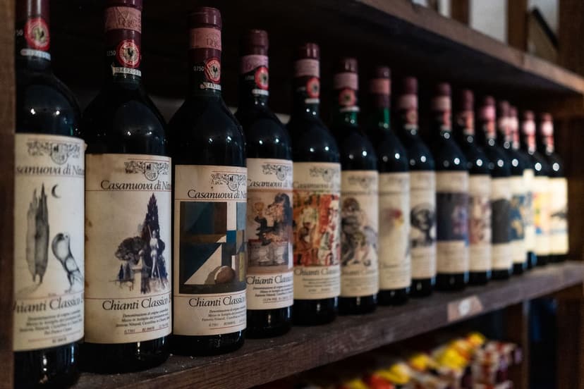 Chianti Classico wine bottles with Gallo Nero labels lined up on a wooden shelf