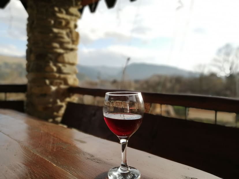 Glass of red wine on wooden table in Sicily with stone loggia and mountain view