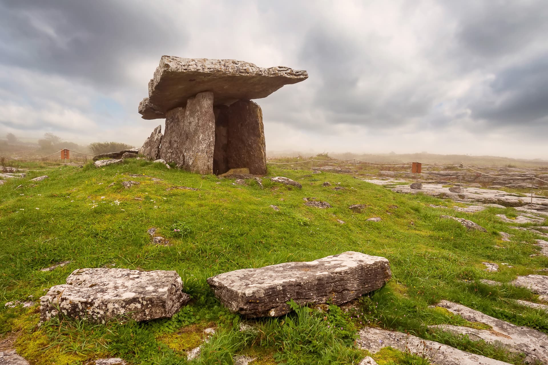 Poulnabrone dolmen portal tomb on grassy karst landscape near Ballyvaughan under cloudy sky.