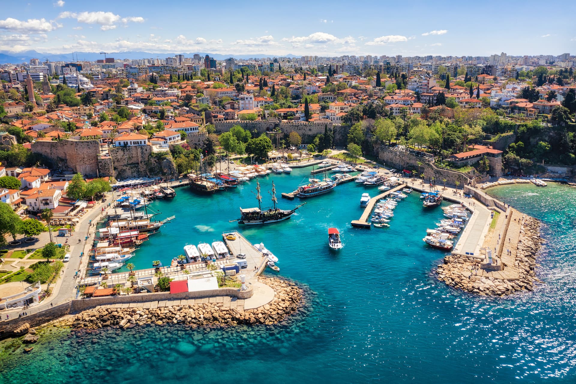 Antalya harbor with historic town, boats, and clear turquoise Mediterranean water.