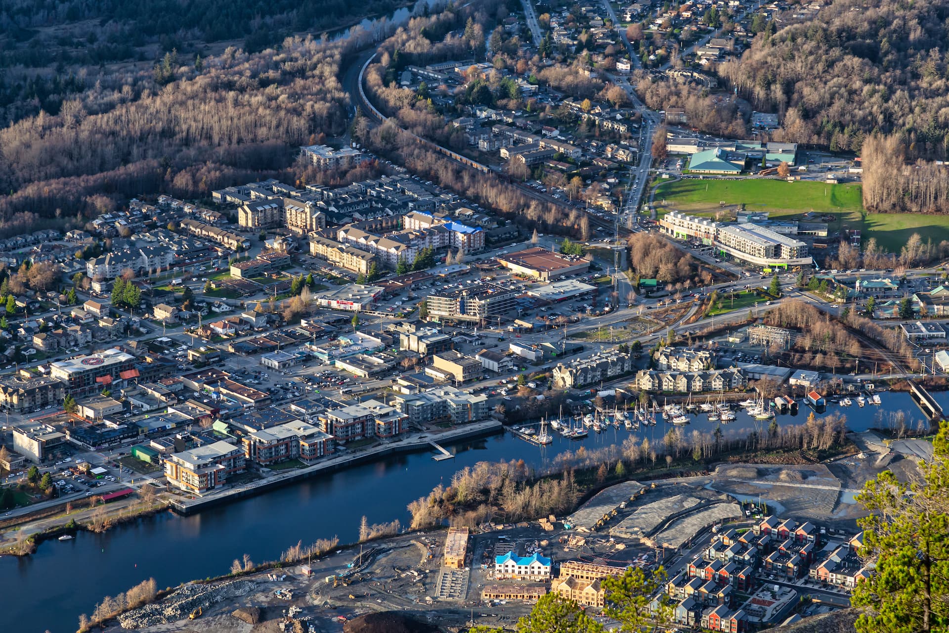 Aerial view of Squamish town with river, marina, and forested mountainsides in autumn.