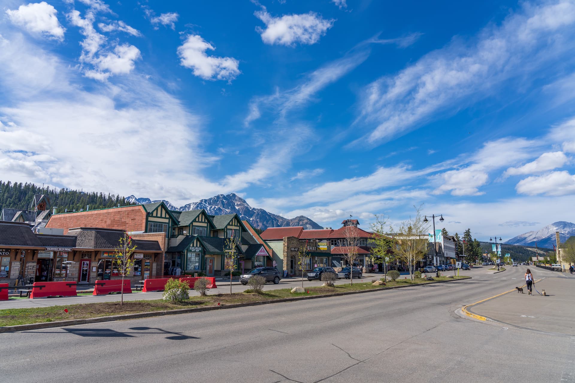 Street view in mountain town with shops and snow-capped peaks under blue sky