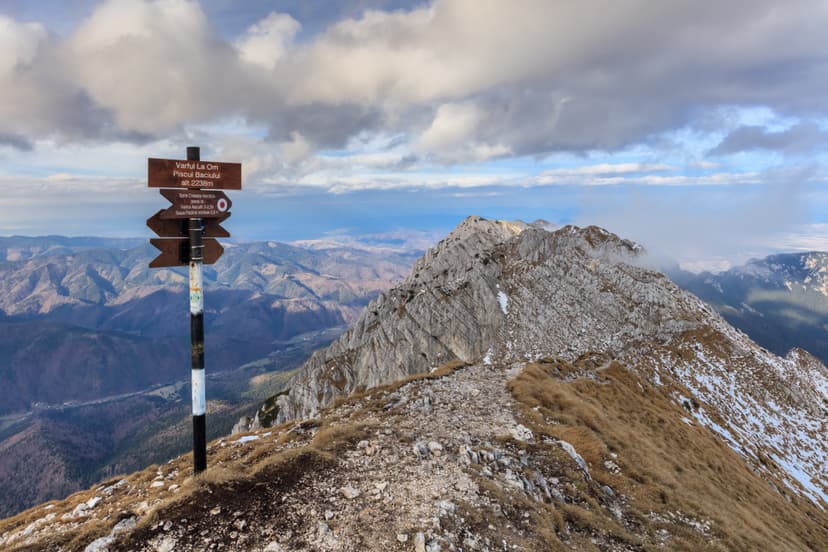 Hiking trail signpost on mountain ridge overlooking alpine peaks and valleys