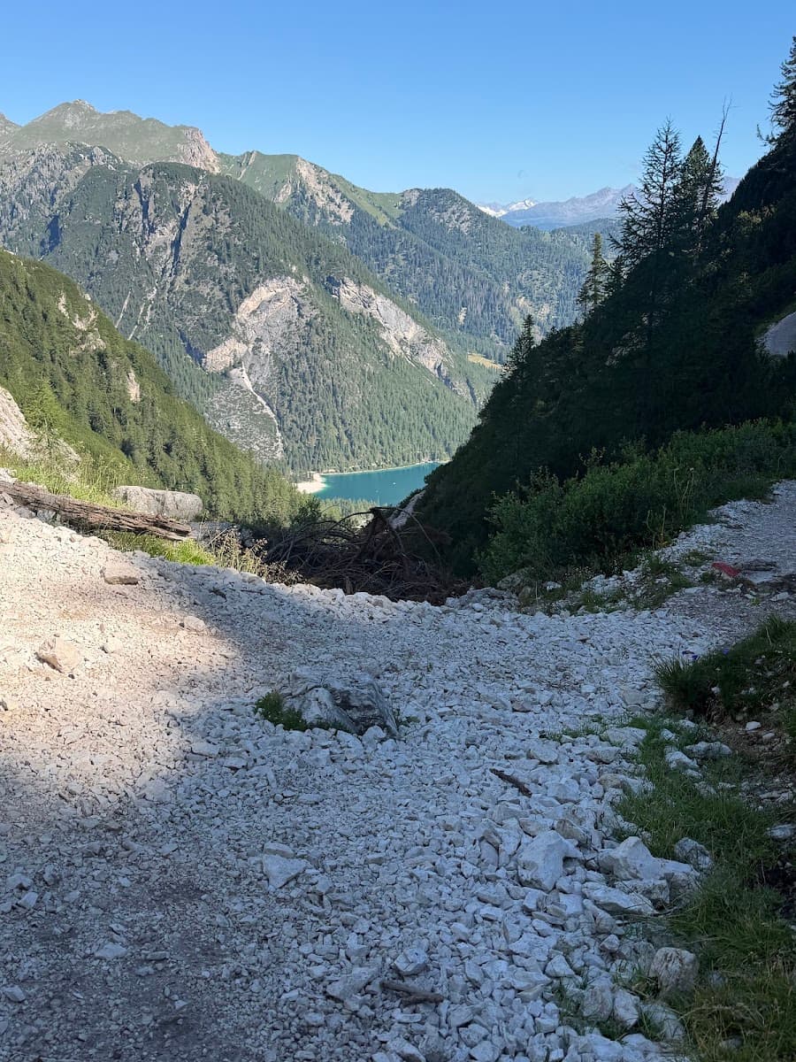 Rocky mountain trail descending toward an alpine lake and forest valley