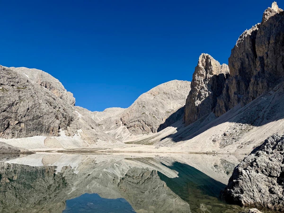Alpine lake reflecting rugged rocky mountain peaks under a clear blue sky