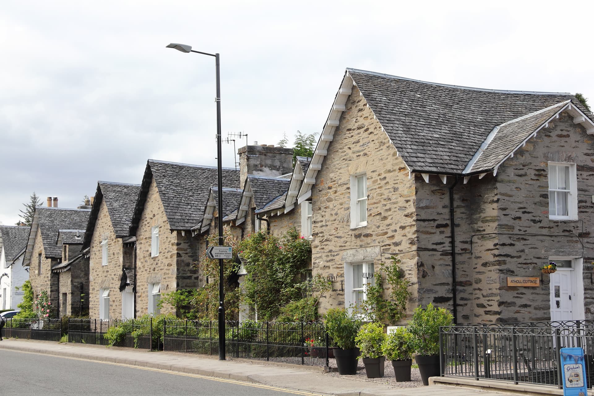 Stone cottages with slate roofs lining a street with a lamppost in Pitlochry.