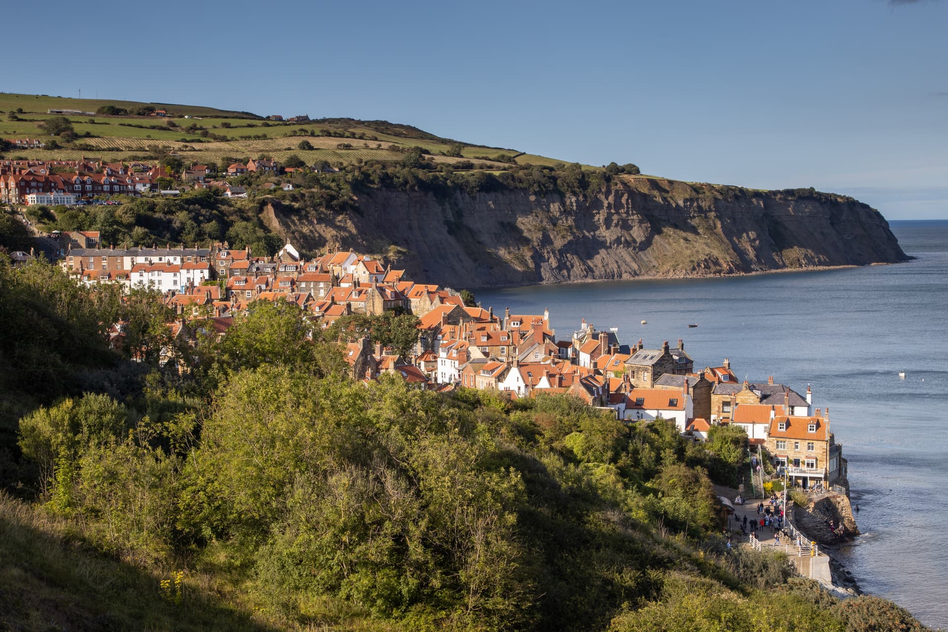 Robin Hood's Bay village nestled against cliffs overlooking the sea under a clear blue sky.