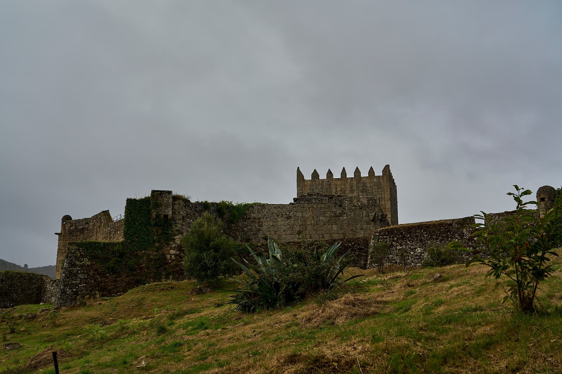 Castle of Lindoso ruins on grassy hill under an overcast sky in northern Portugal.
