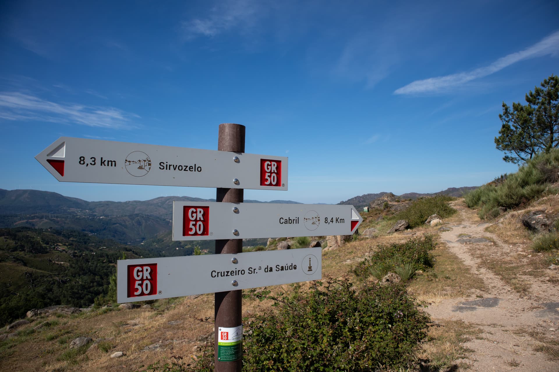 GR 50 hiking signpost showing distances to Sirvozelo and Cabril on a sunny mountain trail.