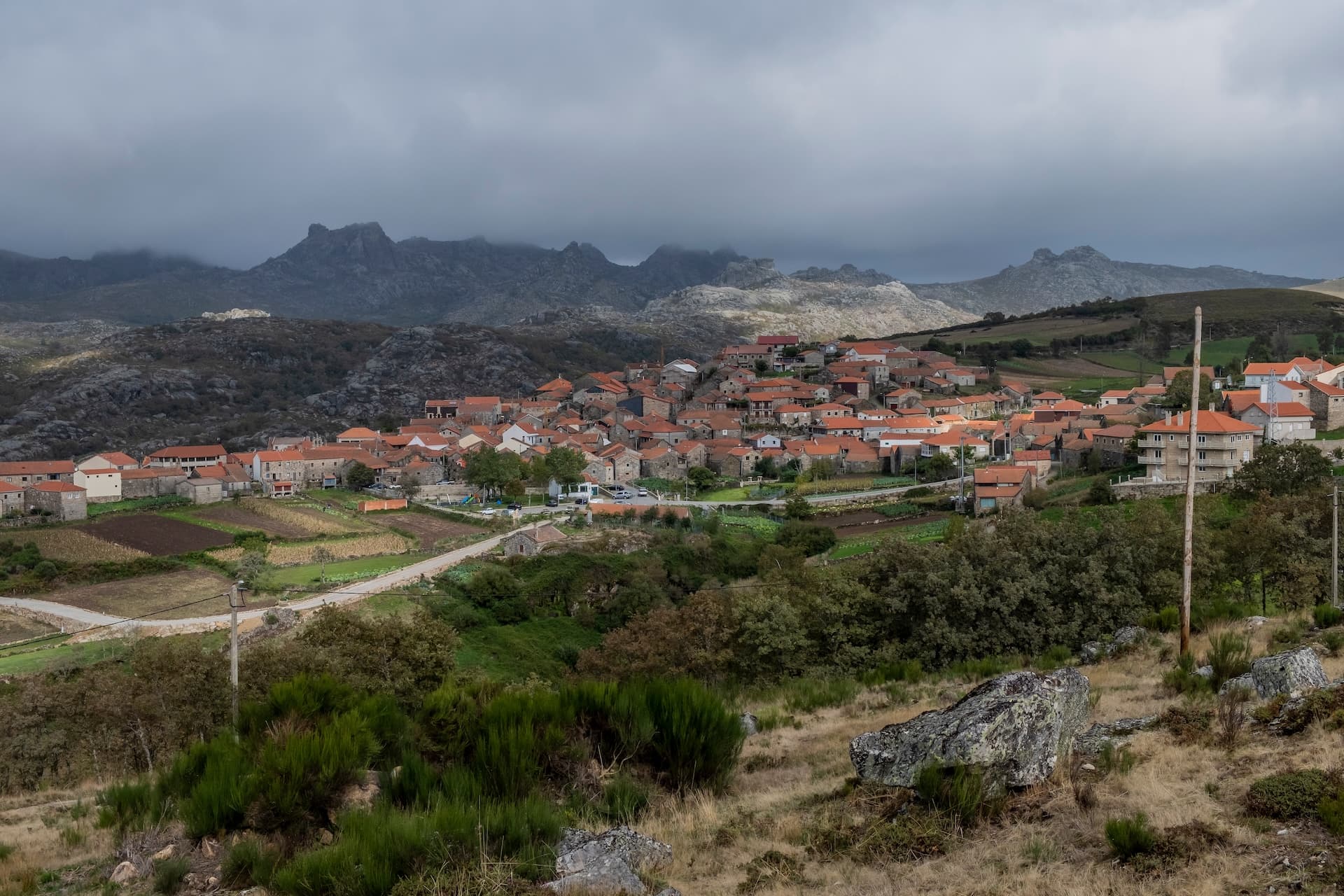 Village of Pitoes das Junias nestled below rocky, cloud-shrouded mountains.