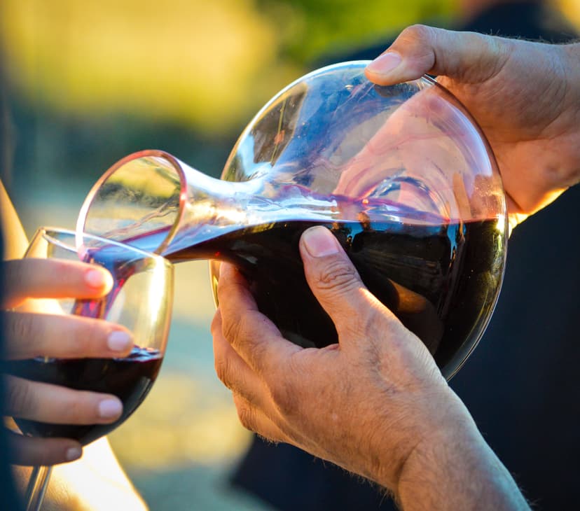 Pouring red wine from a glass decanter into a wine glass