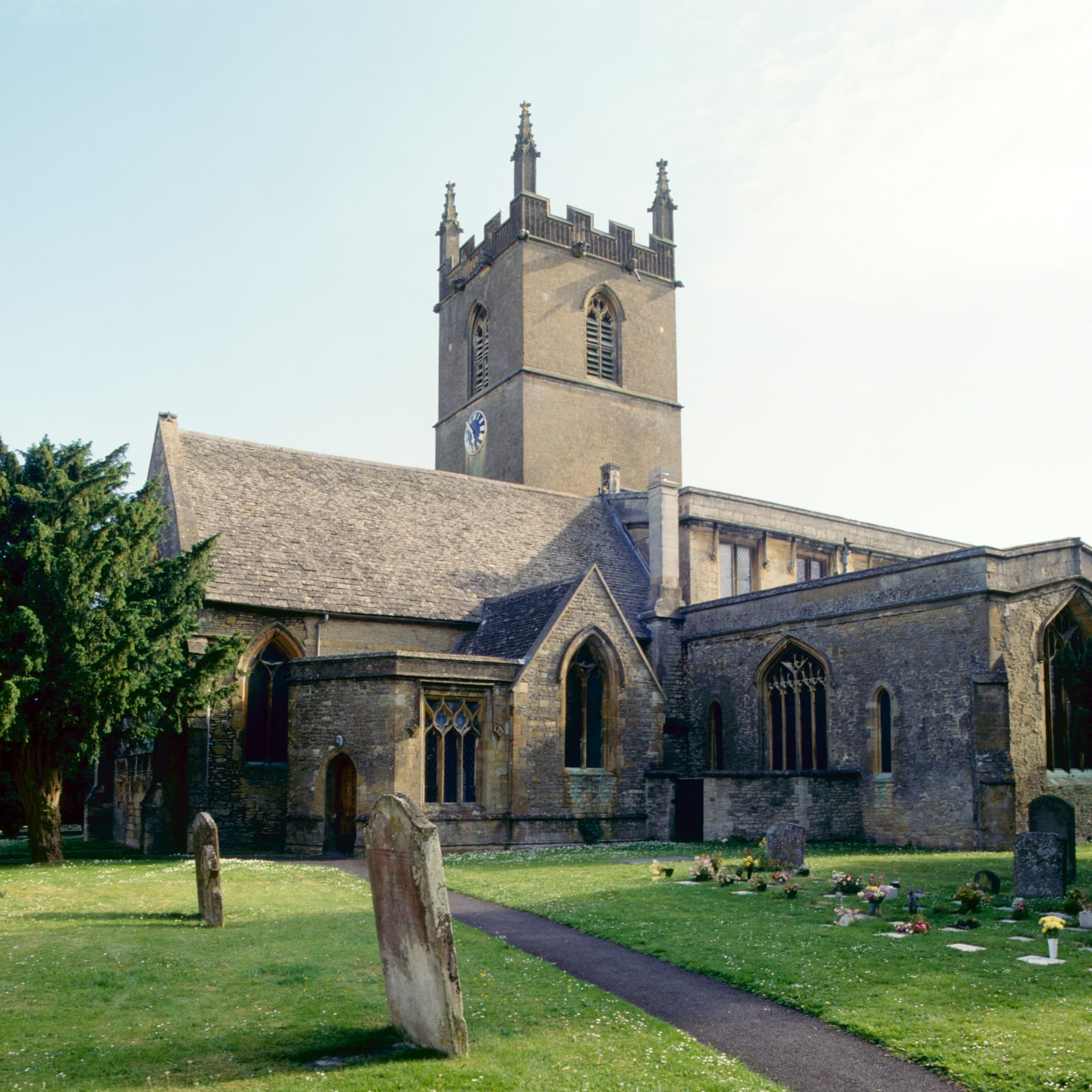 Stone church with tower and clock in graveyard, Stow-on-the-Wold, Cotswolds.