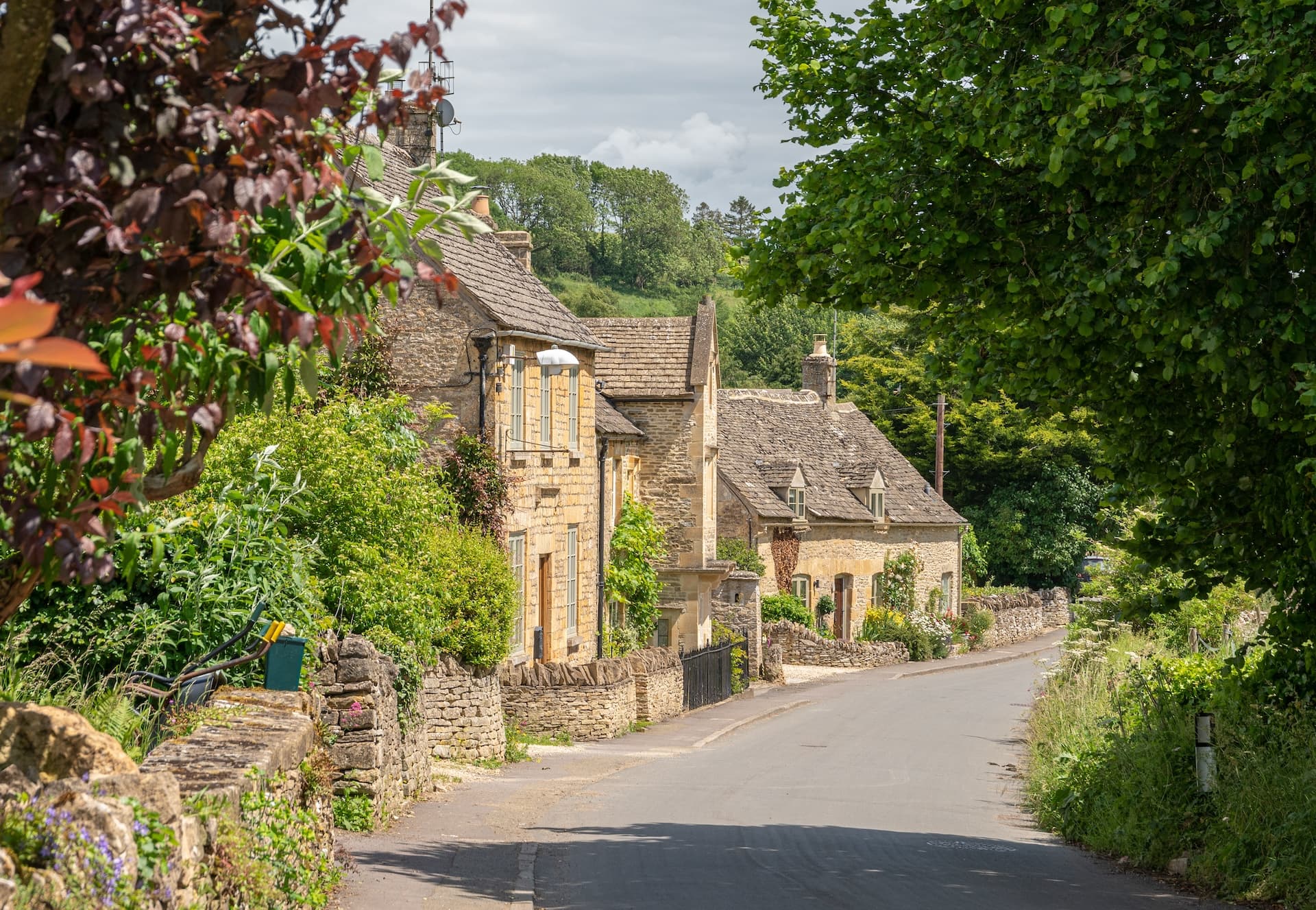 Stone cottages line a winding road in the picturesque Cotswold village of Naunton.