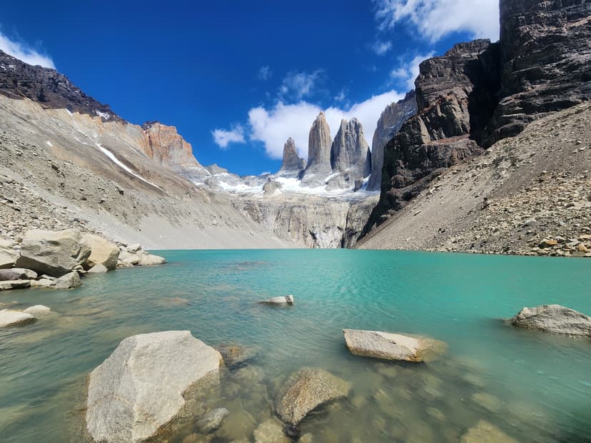 Turquoise alpine lake with rocky shores and jagged mountain peaks under blue sky