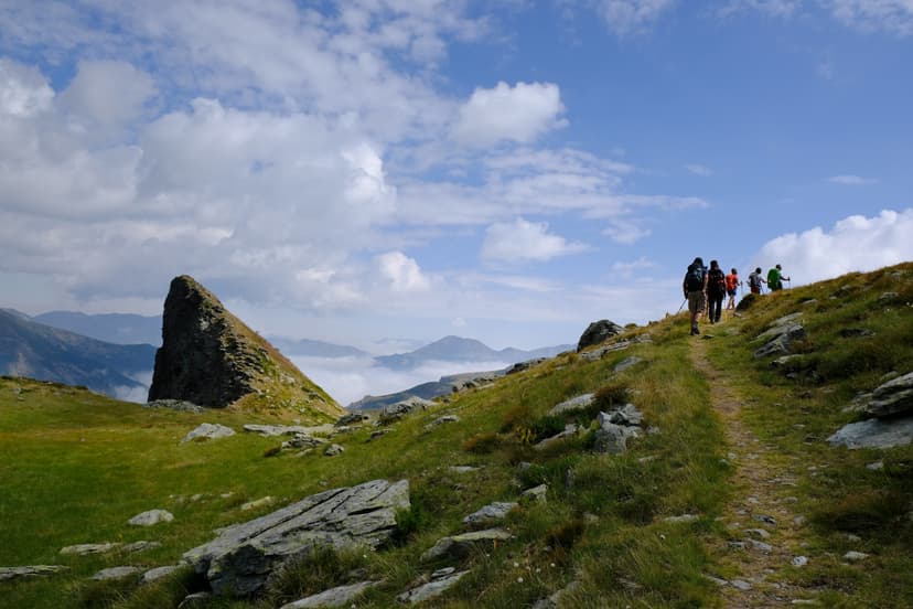 Hikers on a mountain trail with rocky terrain and valley clouds