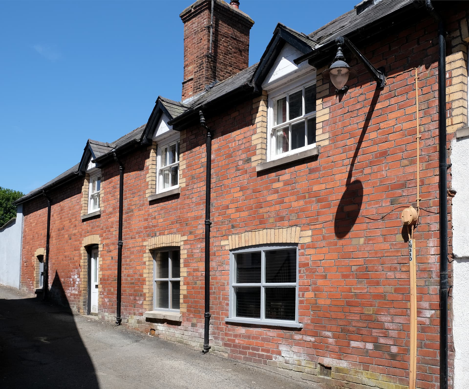 Terraced red brick building exterior with white windows under a clear blue sky in Knighton Street.