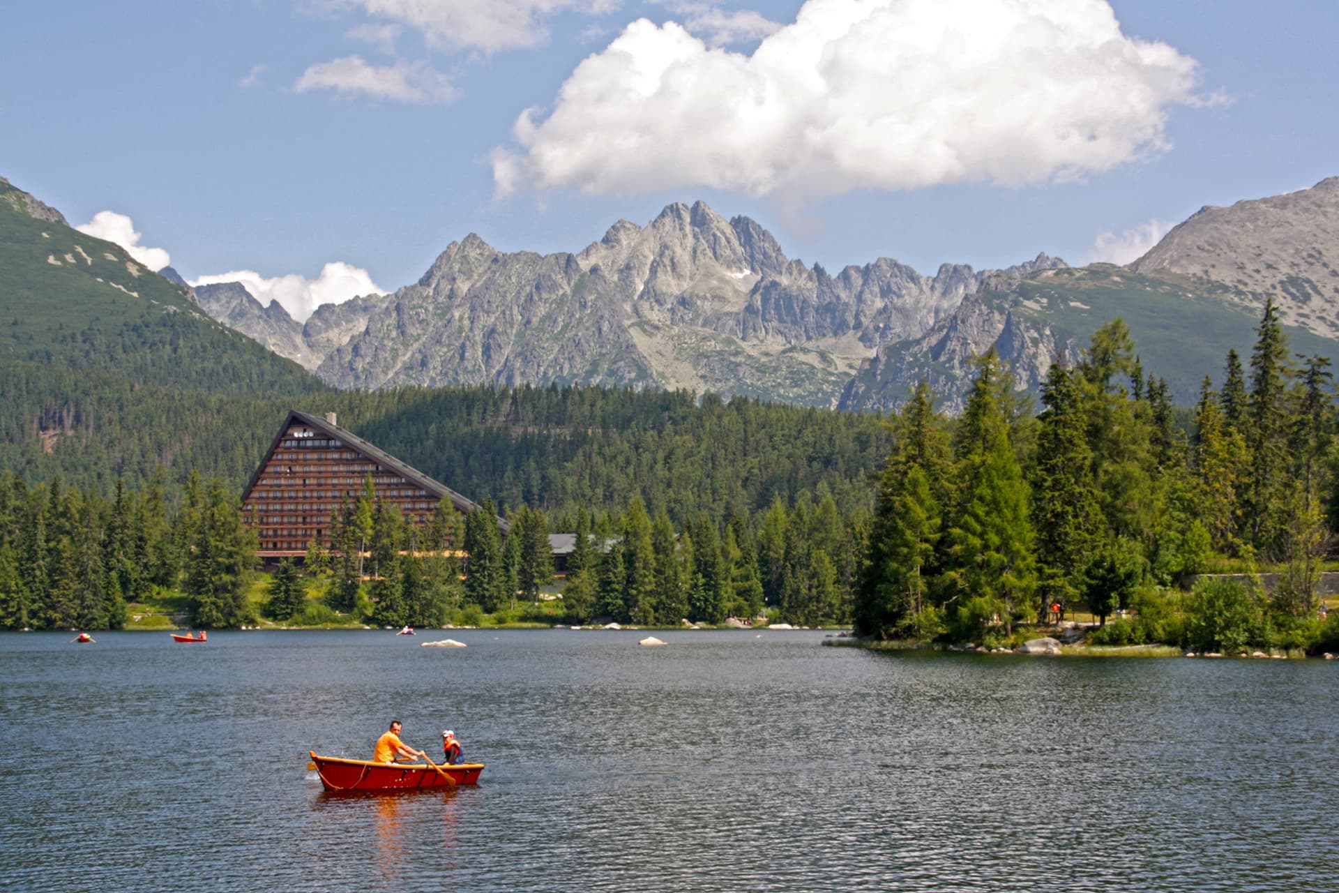 Rowing on Štrbské Pleso lake with mountains and forest in the background