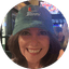 Smiling woman wearing a green baseball cap with Miami text indoors
