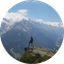 Hiker standing on rocky mountain overlook with snow-covered peaks