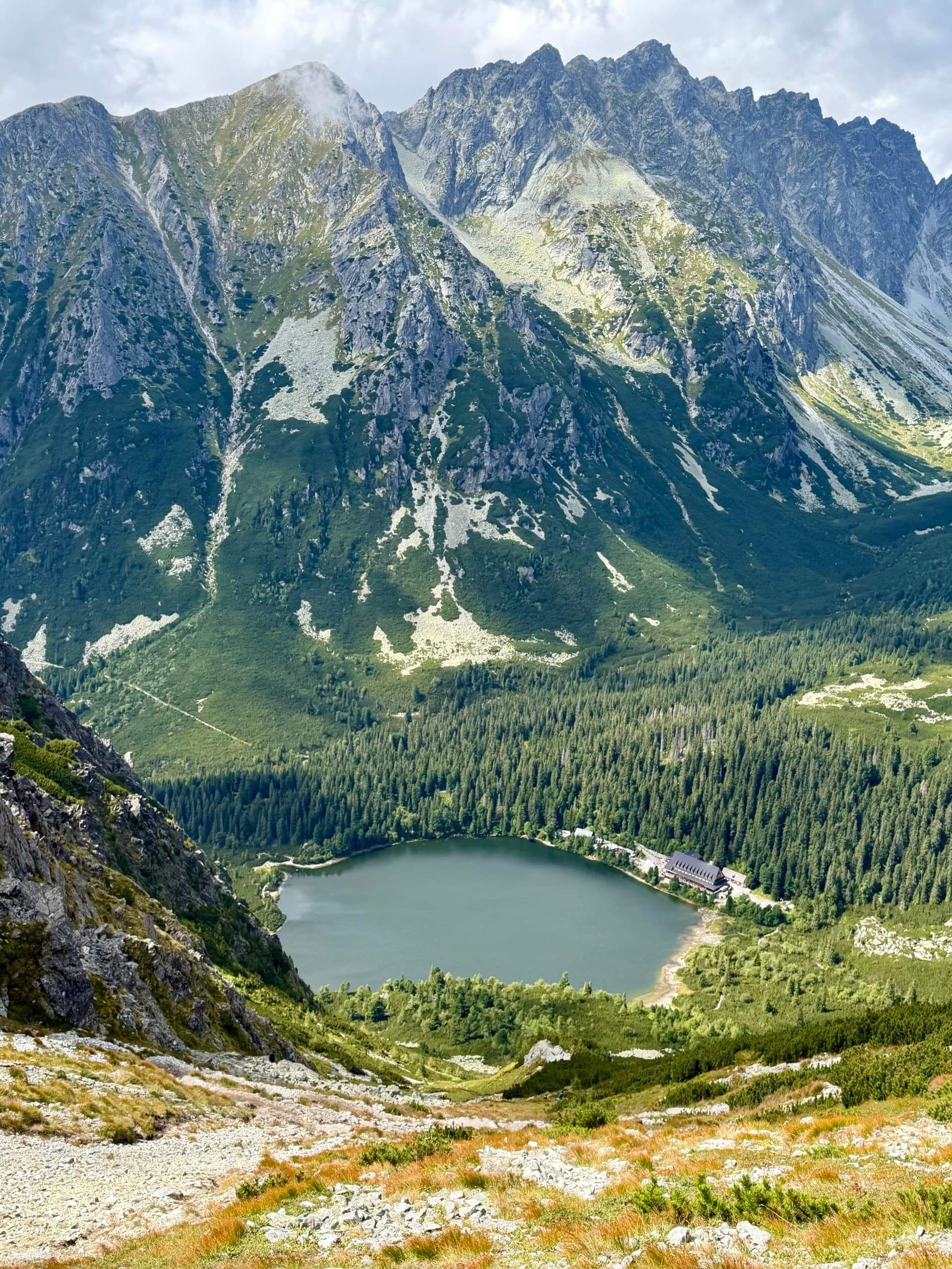 Alpine lake in forested valley surrounded by high rocky mountain peaks
