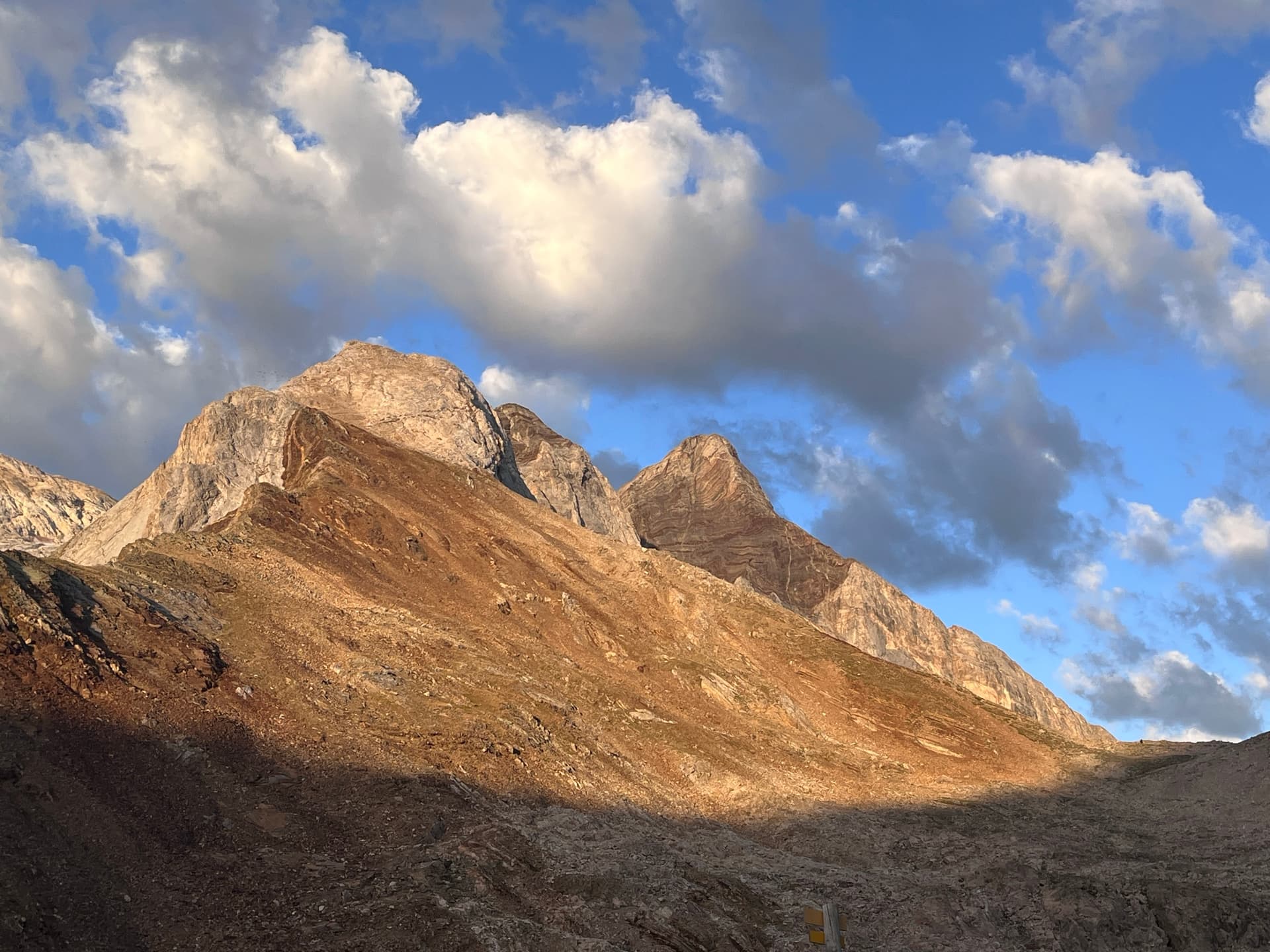 Early morning sunlight on rocky mountain peaks under a blue sky with clouds