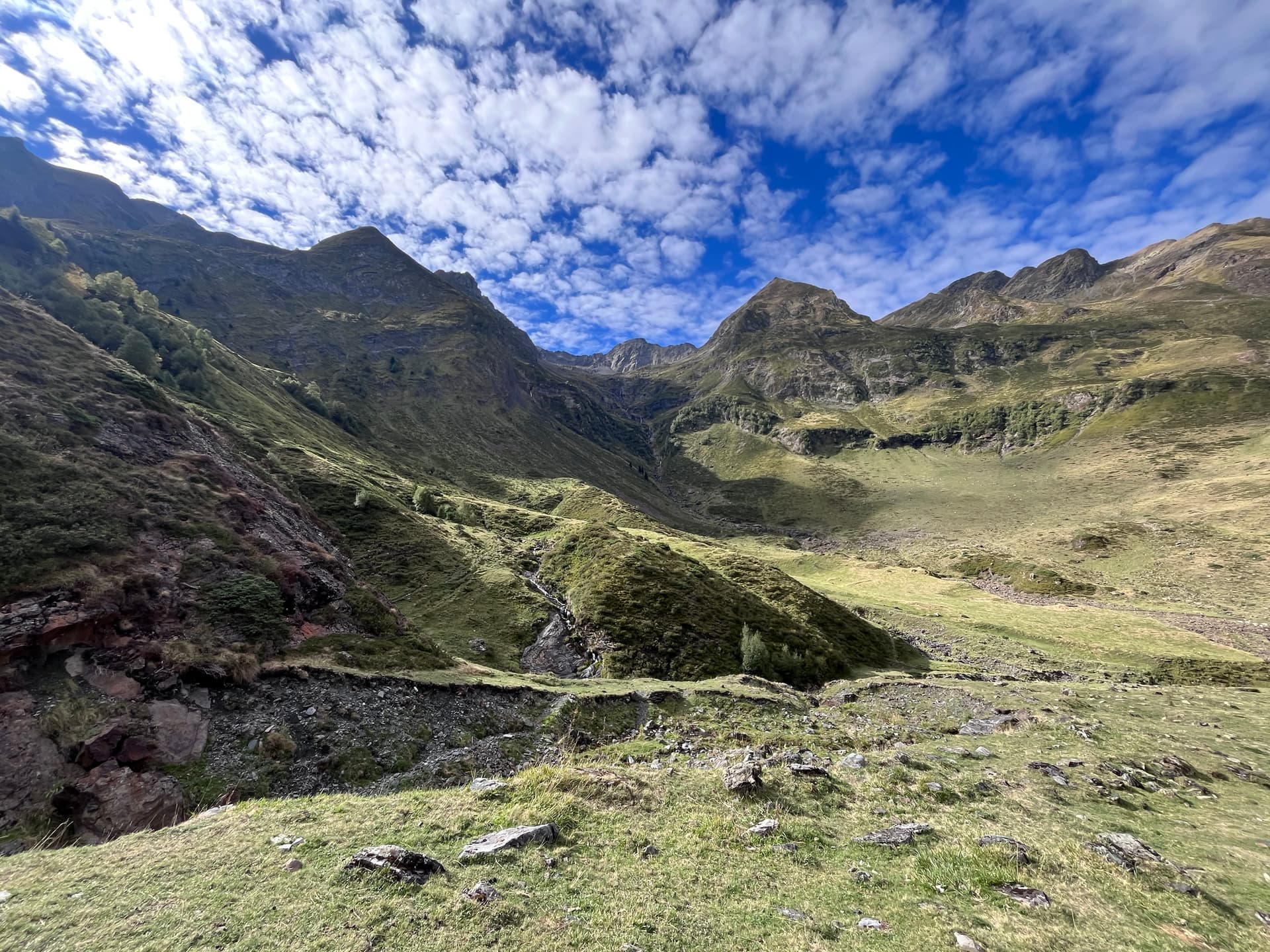 Green mountain valley under small clouds and blue sky
