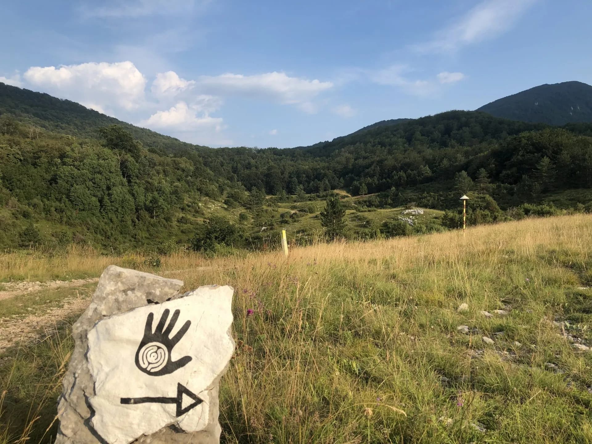 Hiking trail marker on rock with hand symbol pointing right in Učka Nature Park.