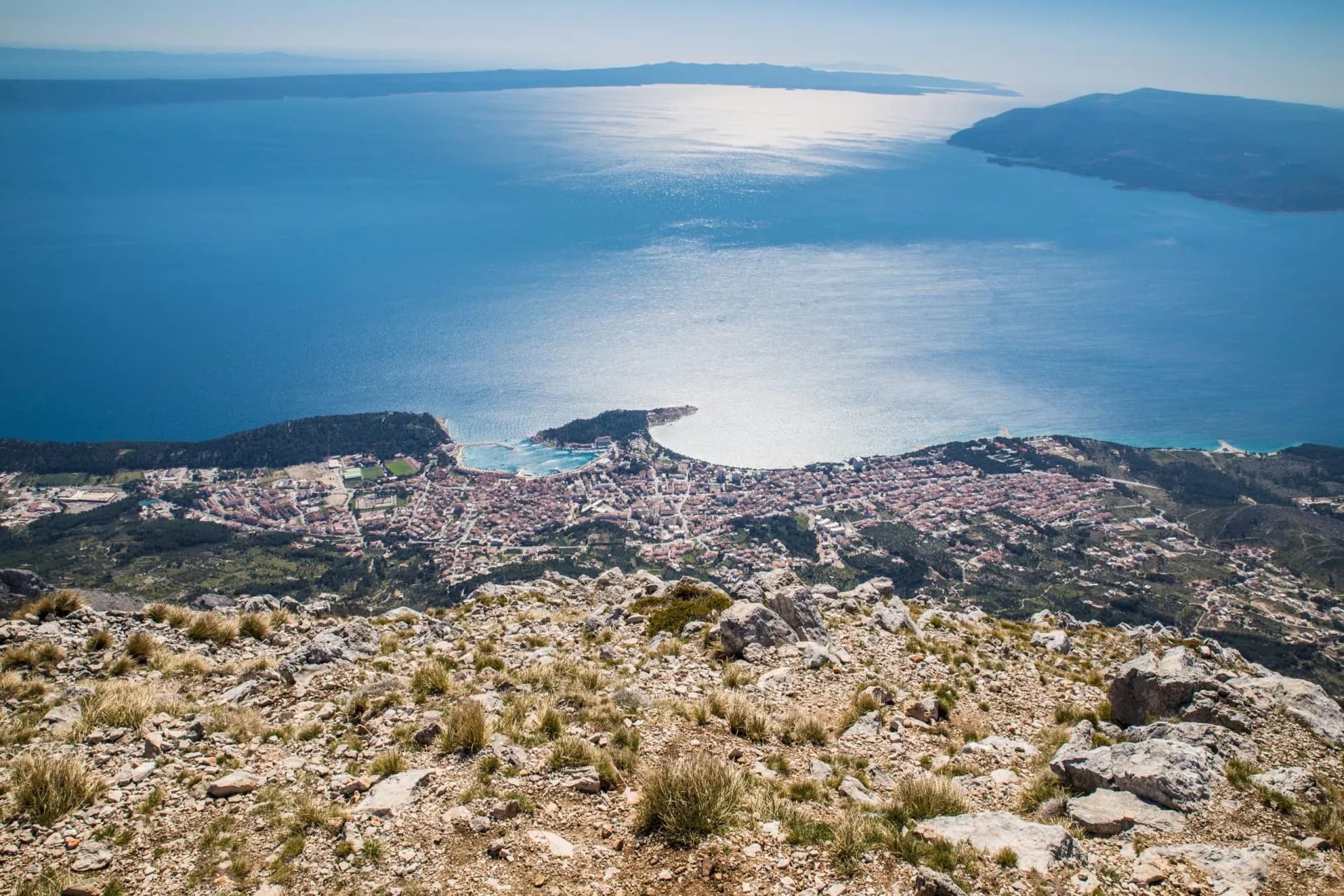 View from rocky Biokovo mountain overlooking coastal town and bright blue Adriatic Sea.