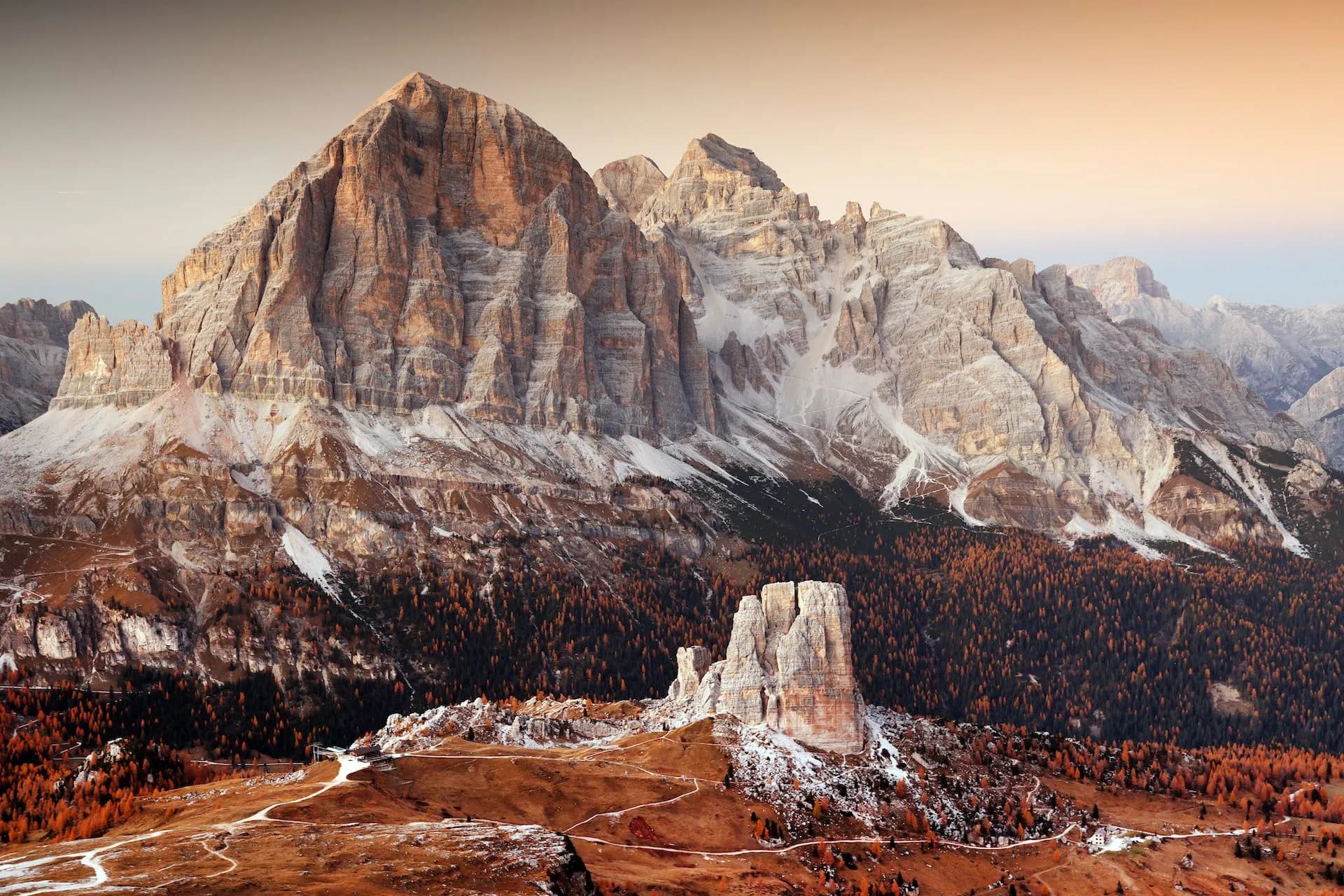 Cinque Torri rock formations and Tofana mountains with autumn trees and light snow.