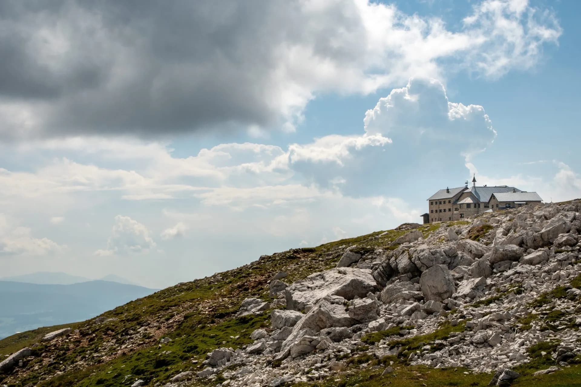 Rifugio Bolzano mountain hut on rocky alpine slope under dramatic clouds on the Schlern Massif.