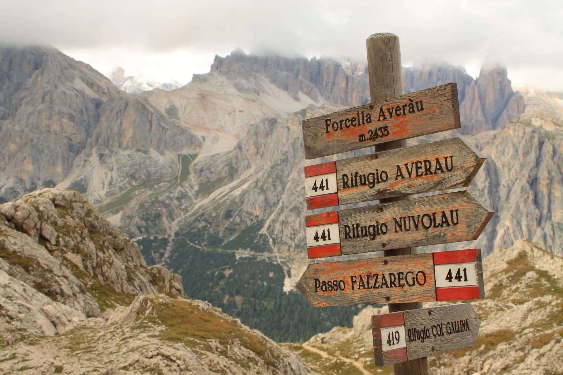 Wooden hiking signpost pointing to Forcella Averàu and Rifugio Nuvola in the rocky mountains.