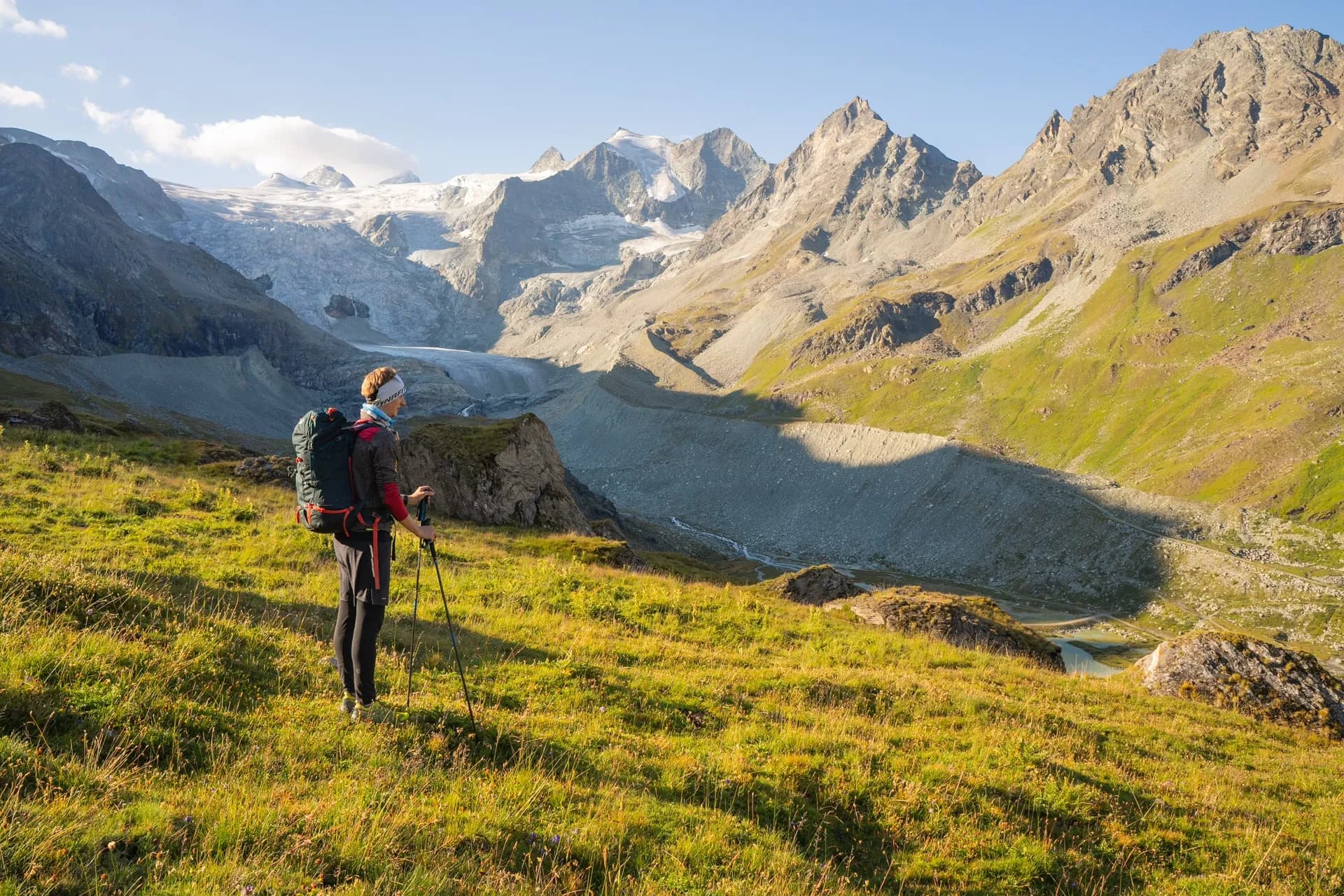 Hiker with backpack and poles overlooking glacier and rocky mountains in Val de Moiry.