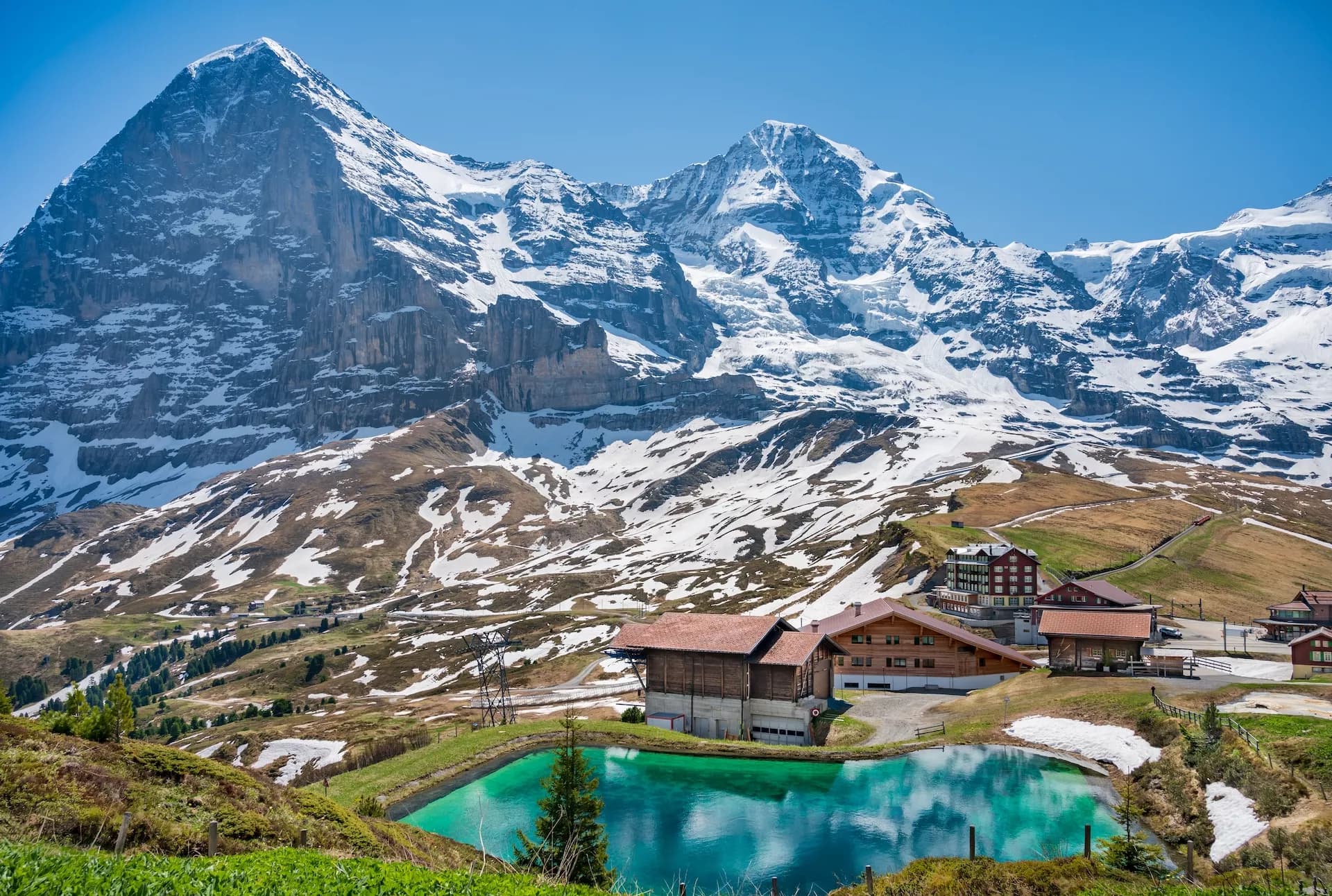 Kleine Scheidegg with Eiger Nordwand background, turquoise pond, and alpine buildings.