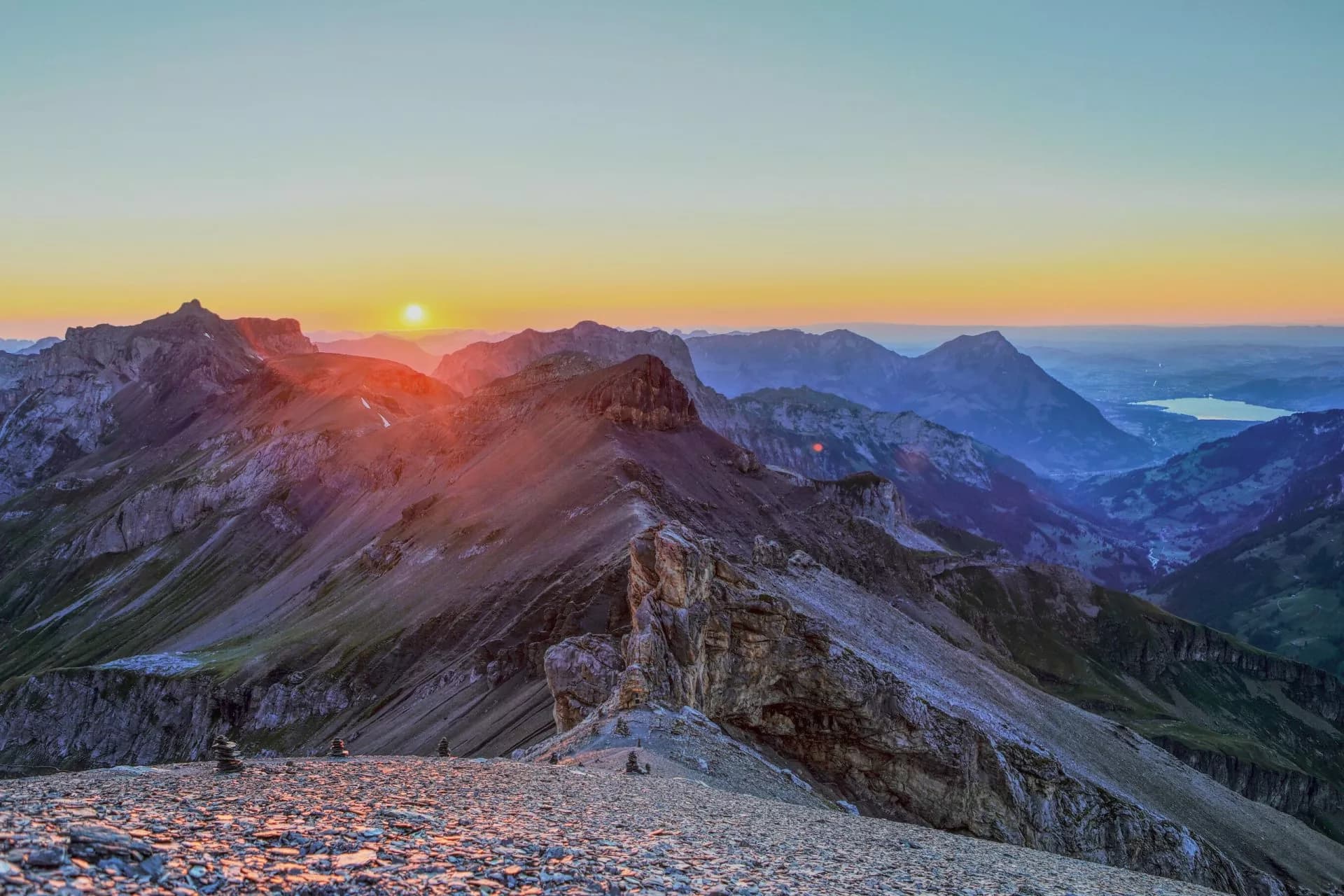 Rocky mountain ridge at sunrise overlooking a valley with a lake, near Bluemlisalphutte.