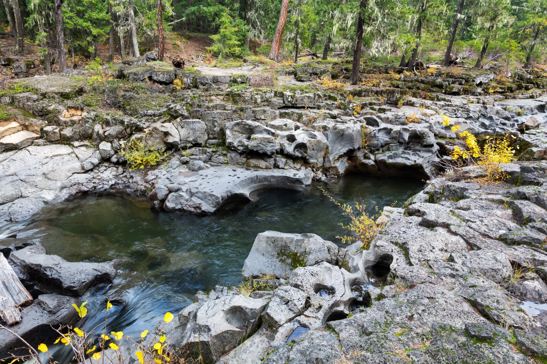 Clear water running between rounded boulders in a rocky river channel