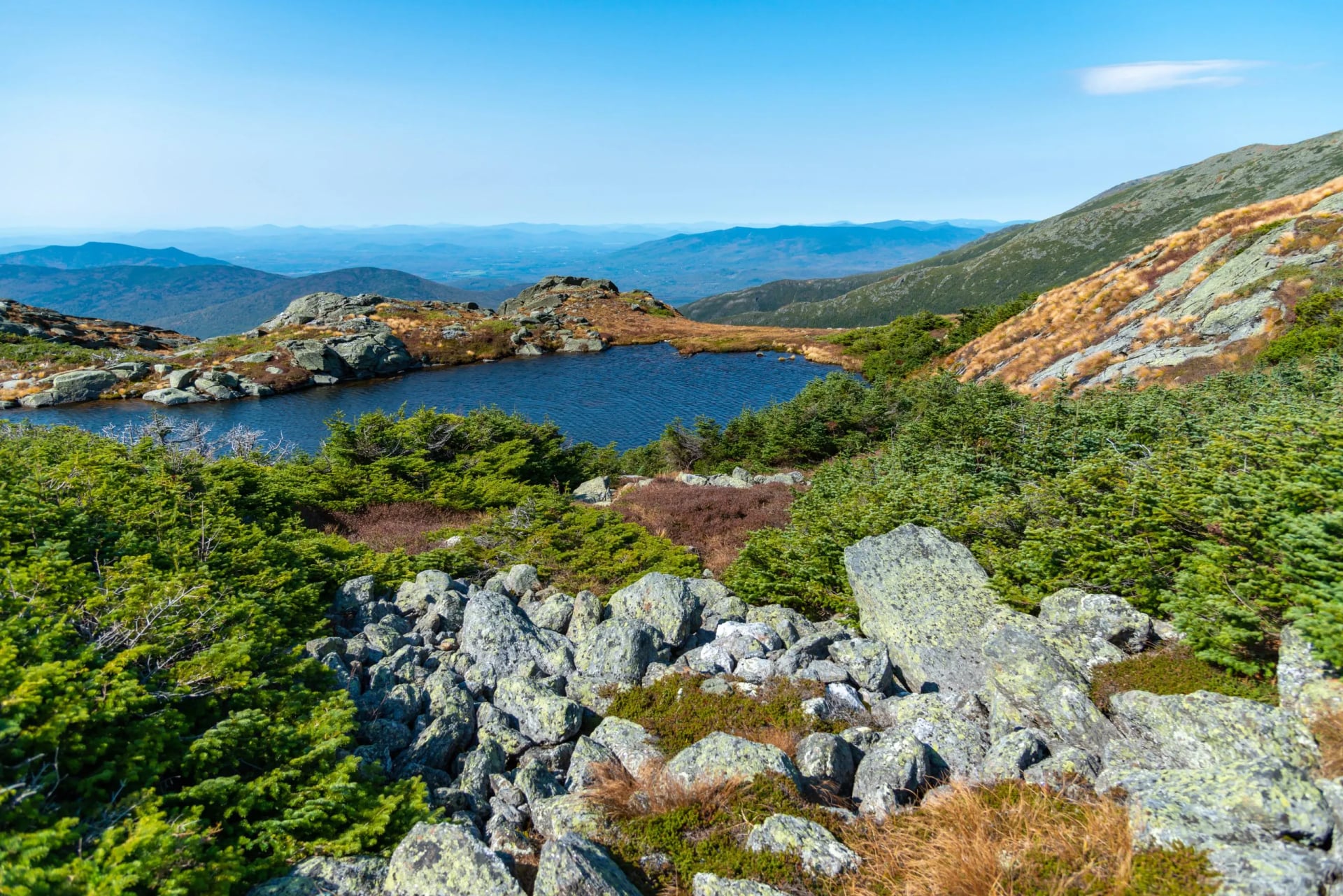 Two small alpine tarns among rock and low scrub on an open ridge