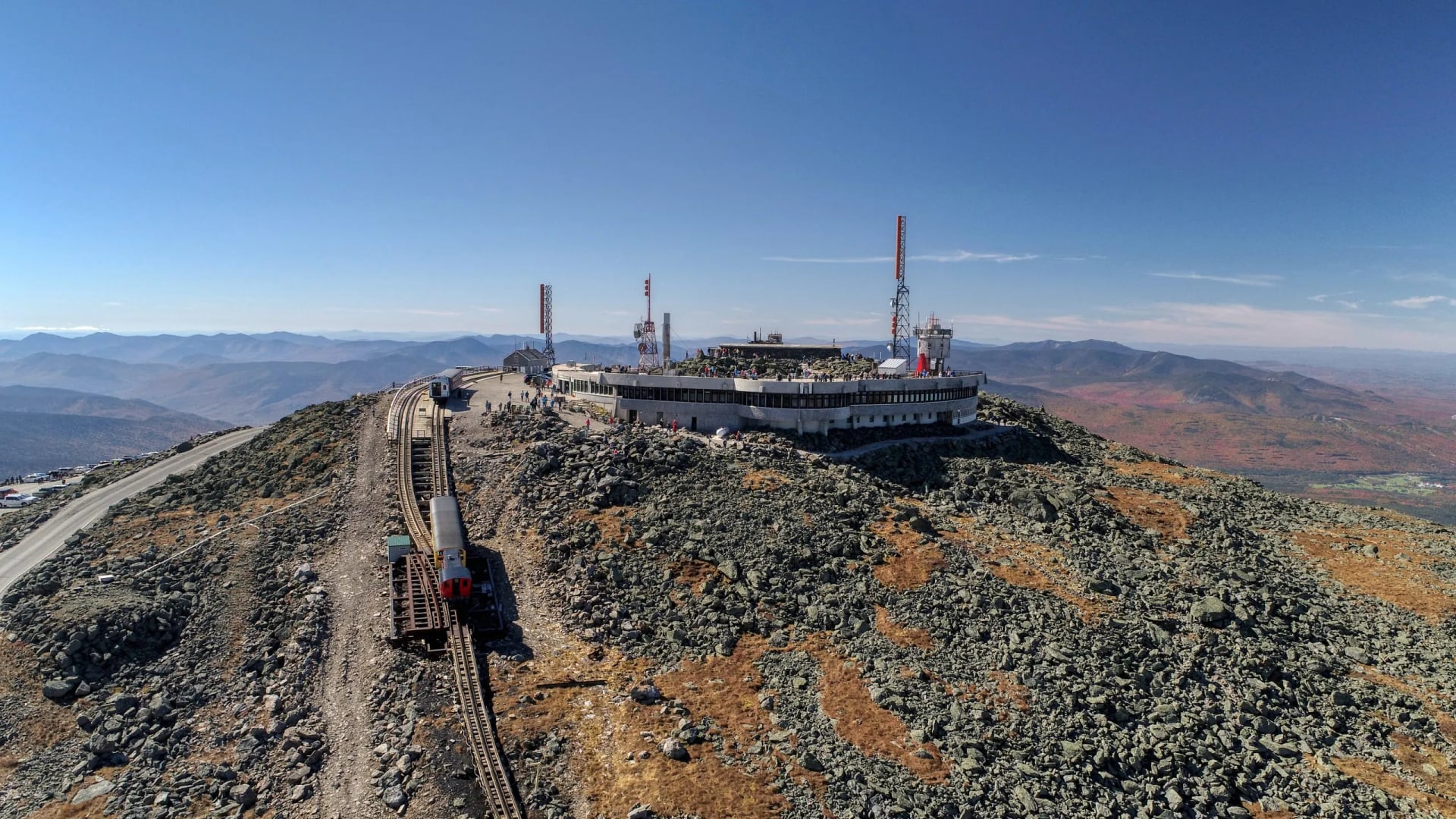 A bare rocky summit plateau with weather buildings masts and a railway track