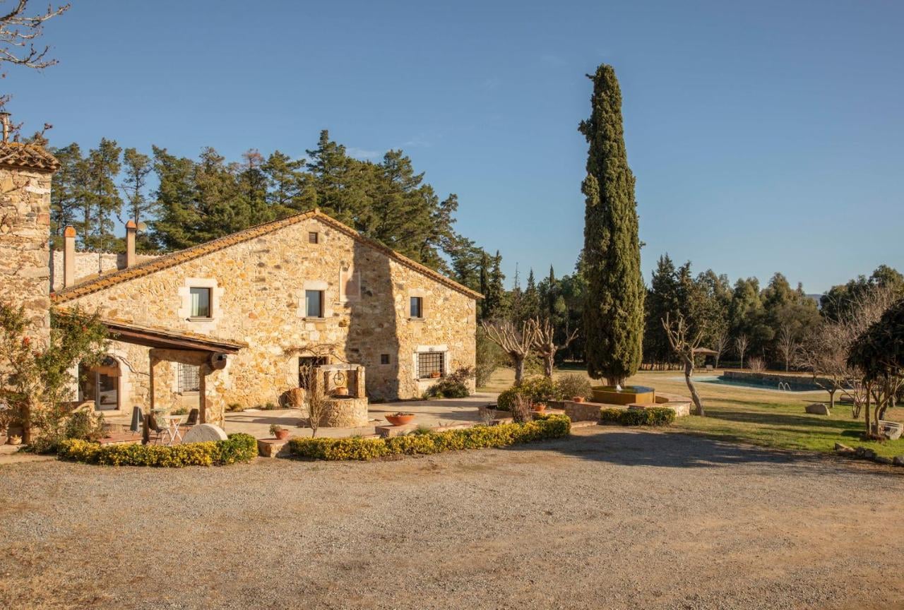 Restored stone masia with cypress trees and a gravel forecourt in the Empordà