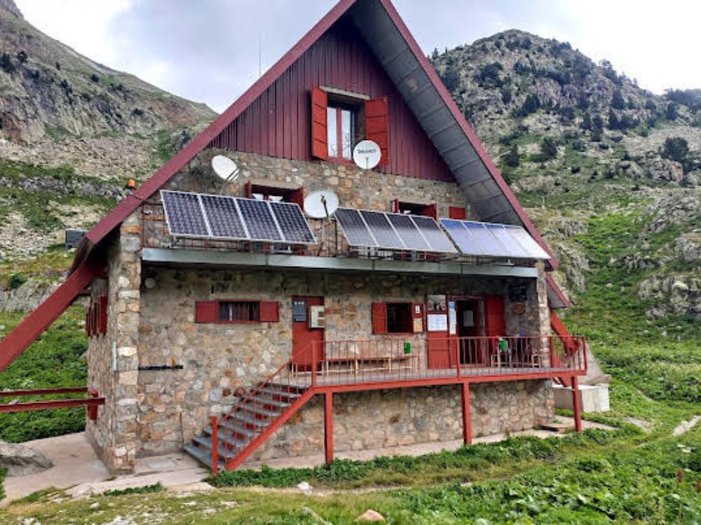 The Refugio de Respomuso a red and stone mountain hut with solar panels on its roof