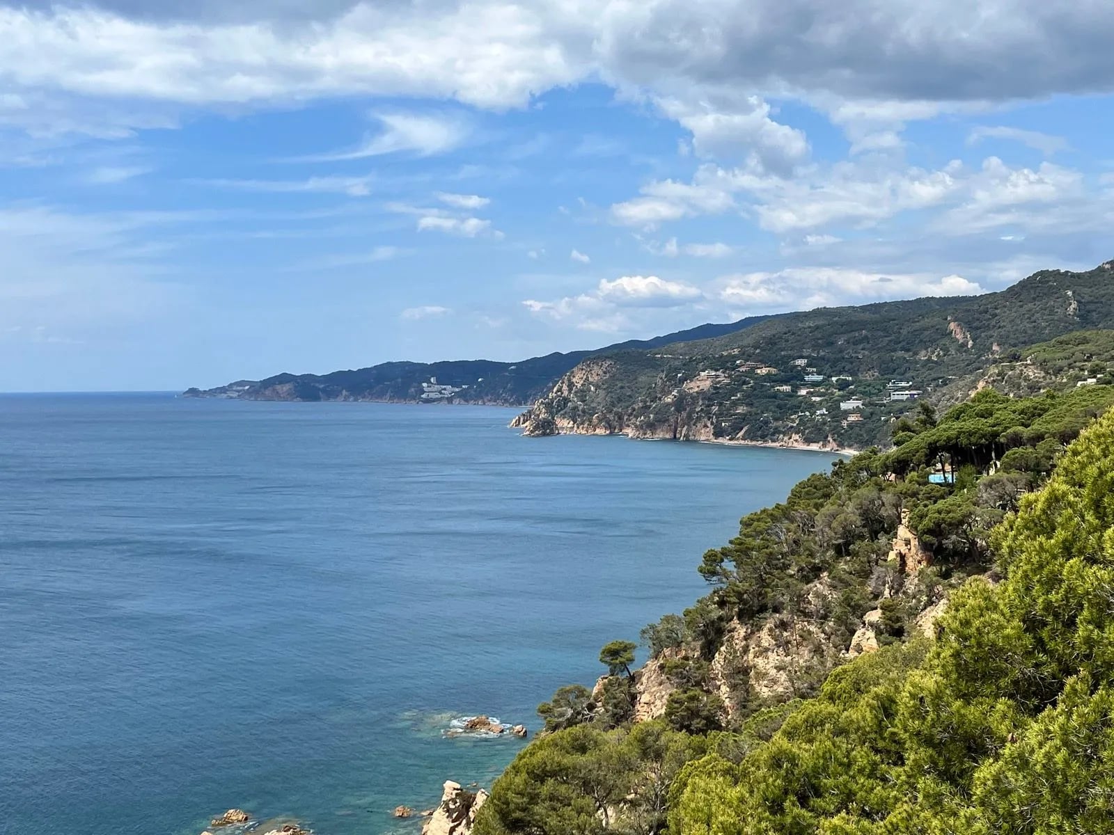 Wooded headlands running away down the Costa Brava coastline above a calm blue sea