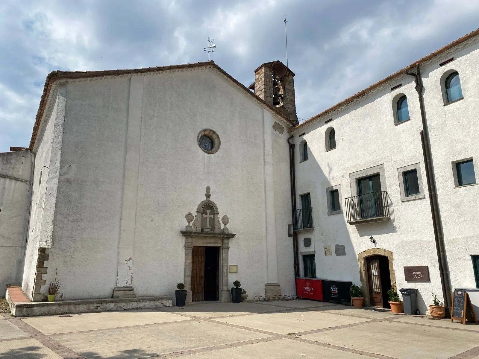 The plain white facade and courtyard of the Santuari dels Àngels above Girona