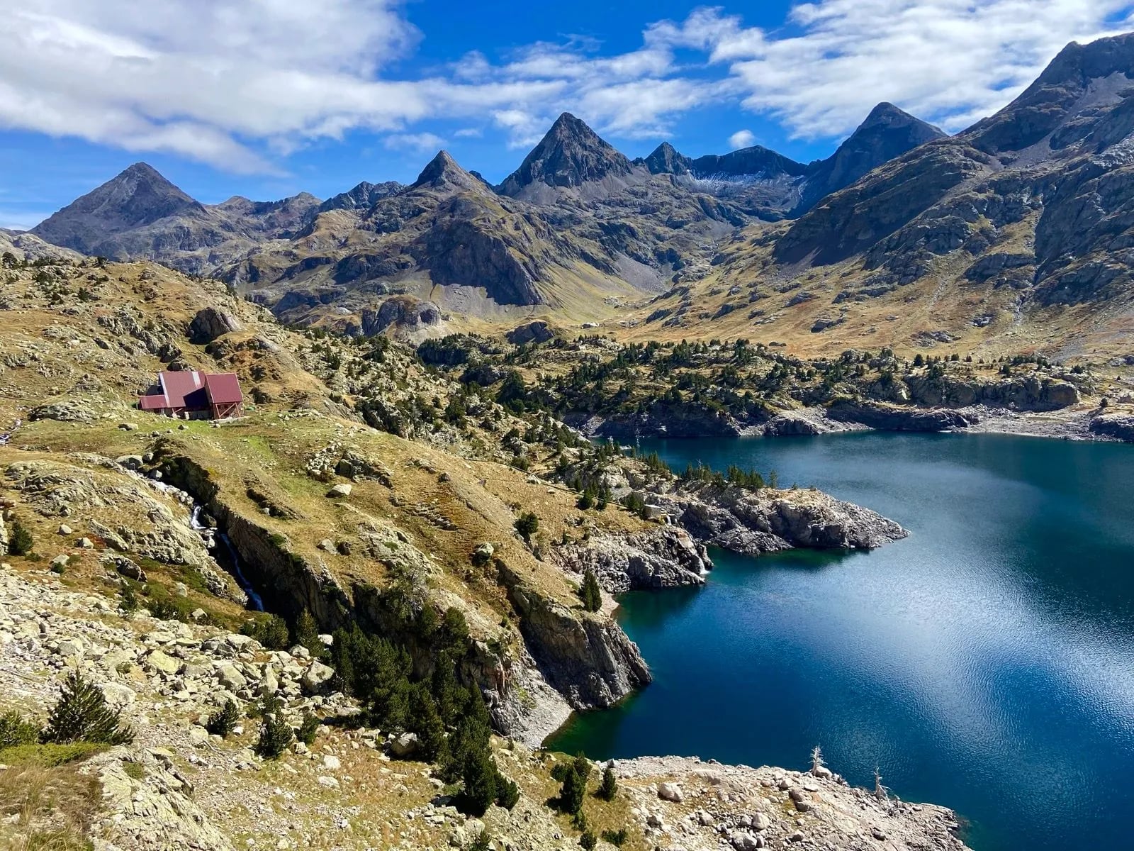 The Ibón de Respomuso under jagged Pyrenean peaks with a refuge on its shore
