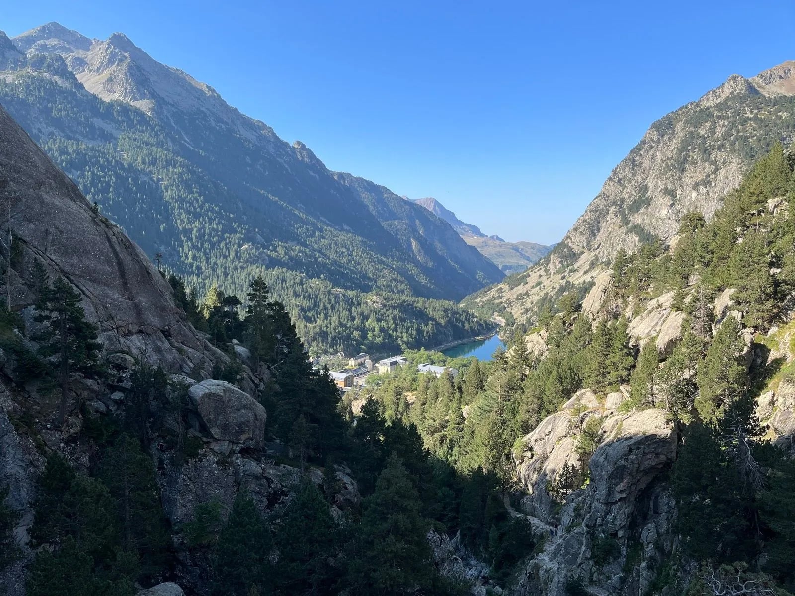 Steep green Pyrenean valley falling away to a small lake far below